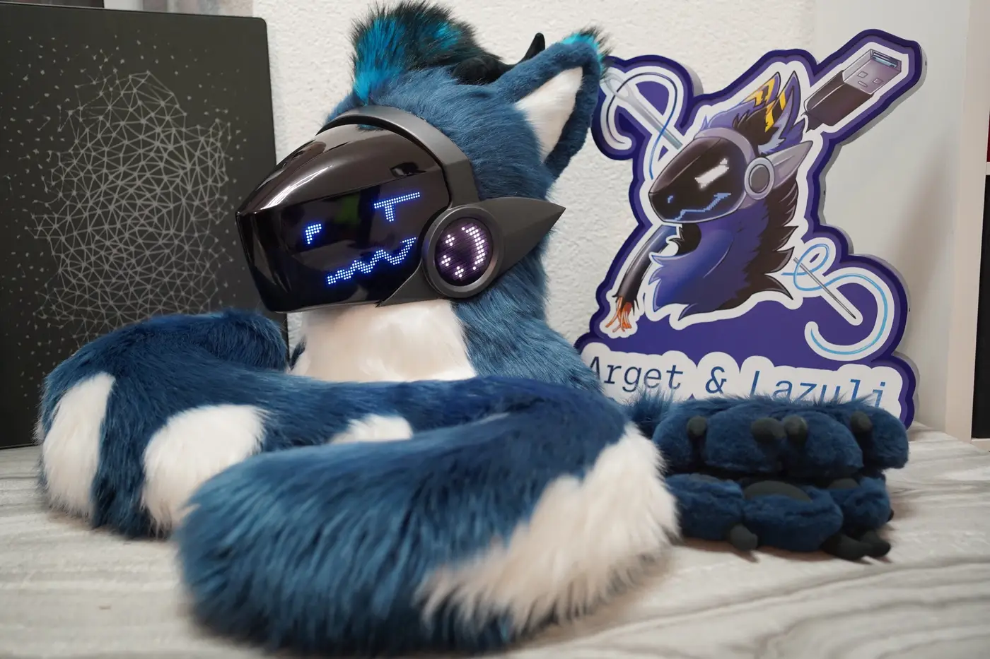 Blue and white Protogen head, hand paws and tail with the Arget and Lazuli logo