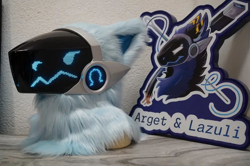 Light blue and silver Protogen head with an angular blue pixel eye and a zigzag mouth on the black LED visor