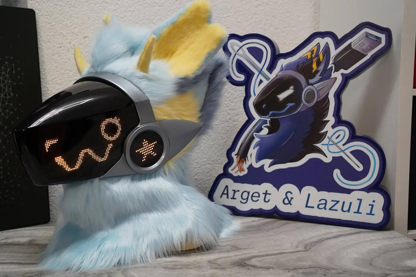 Light blue Protogen head with a wavy yellow pixel mouth on the black LED visor
