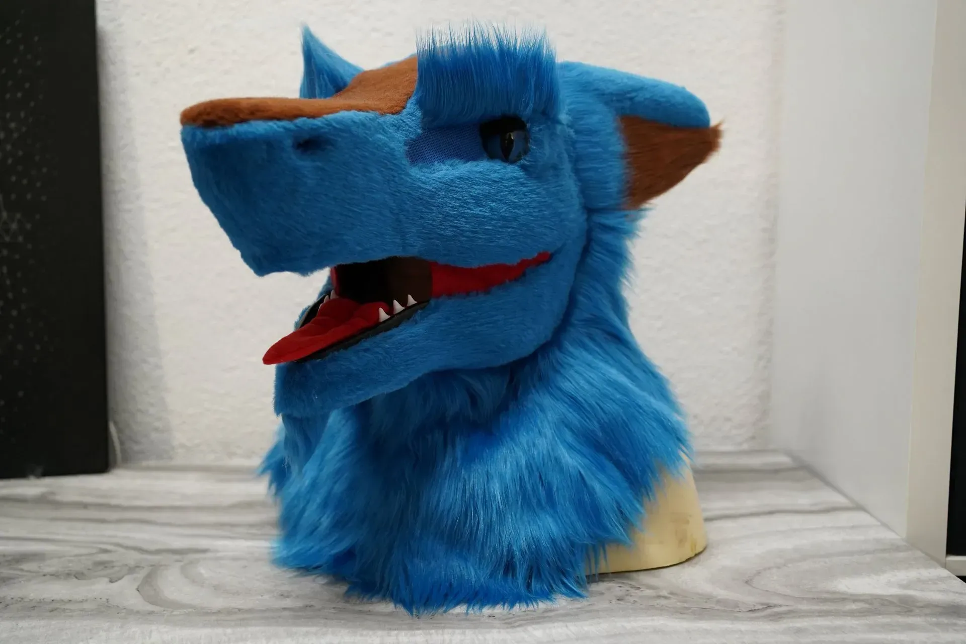 Blue Sergal fursuit head with the mouth open, red tongue and white fangs
