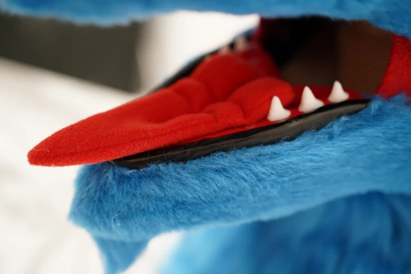 Closeup of a blue Sergal fursuit head maw with a red tongue and sculpted white fangs, by Arget & Lazuli